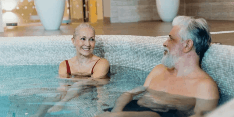 Older couple with white hair sitting together in a hot tub, looking at each other